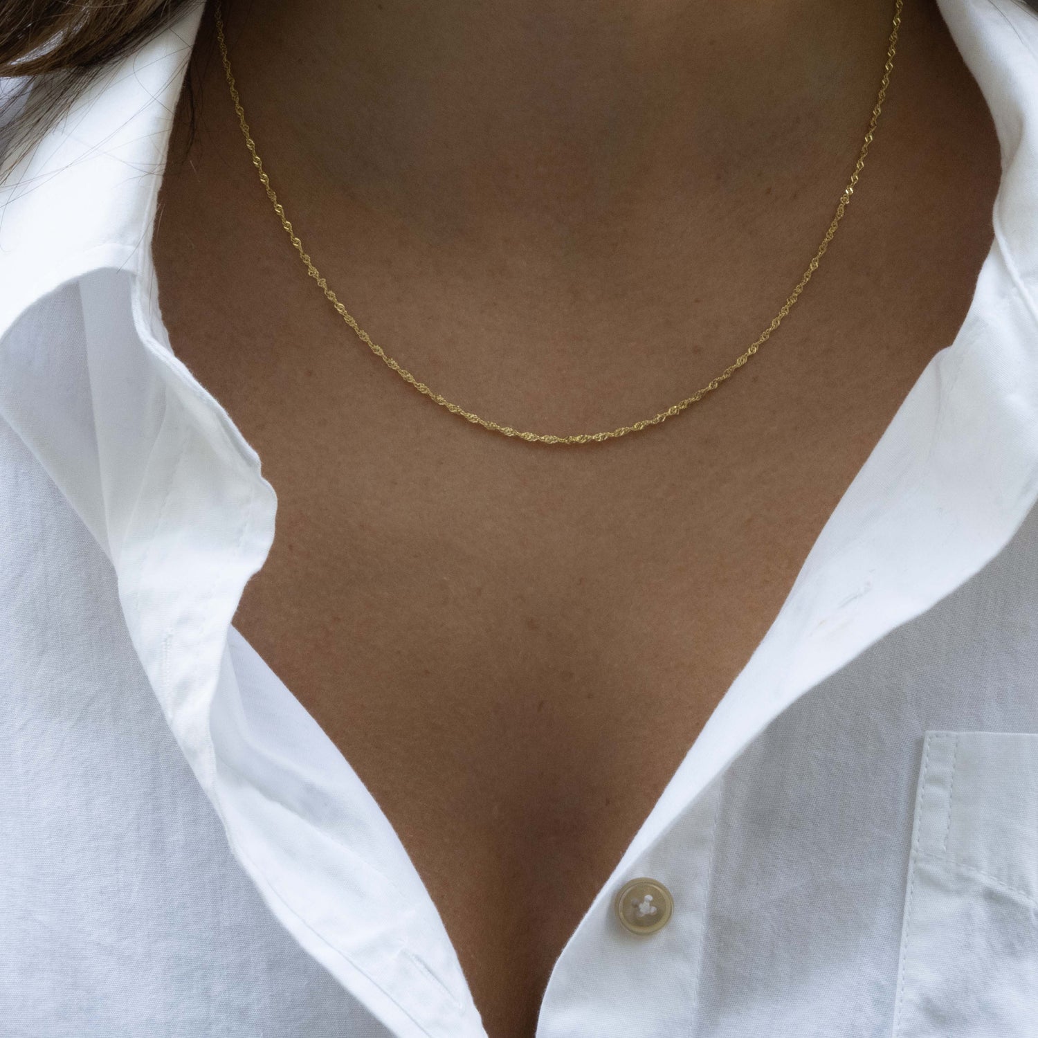 Model wearing dainty gold thin twist chain.