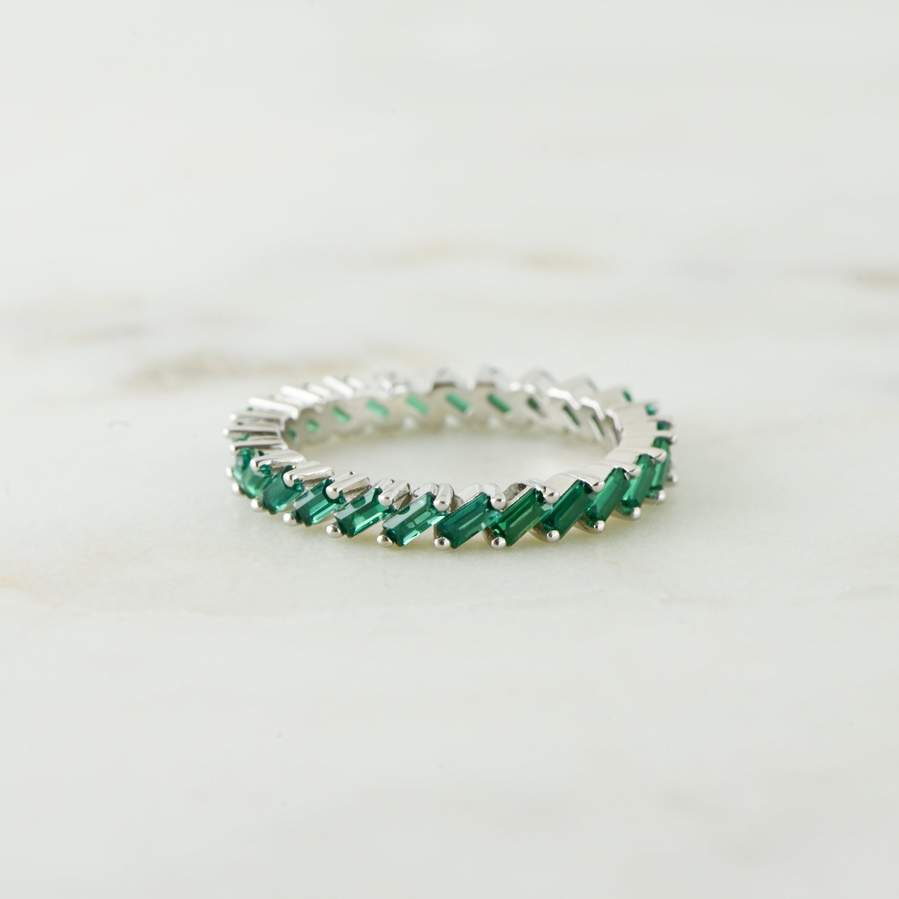 Sterling silver emerald slanted baguette ring in soft studio lighting. 