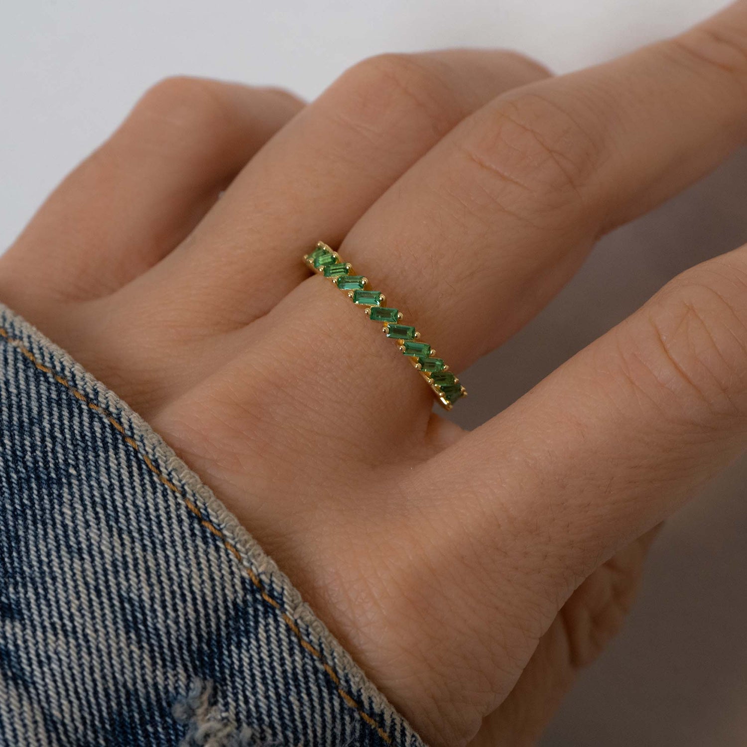 Model wearing gold slanted emerald baguette ring.