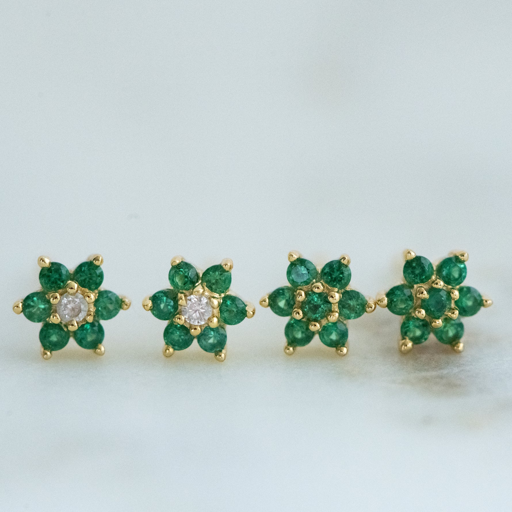 Gold emerald flower stud earrings in two different variations. 