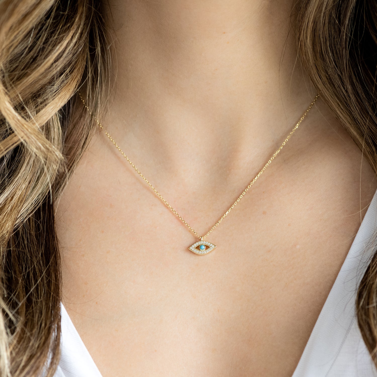 Model wearing dainty turquoise evil eye necklace.