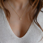 Model wearing delicate gold evil eye studded pendant necklace.