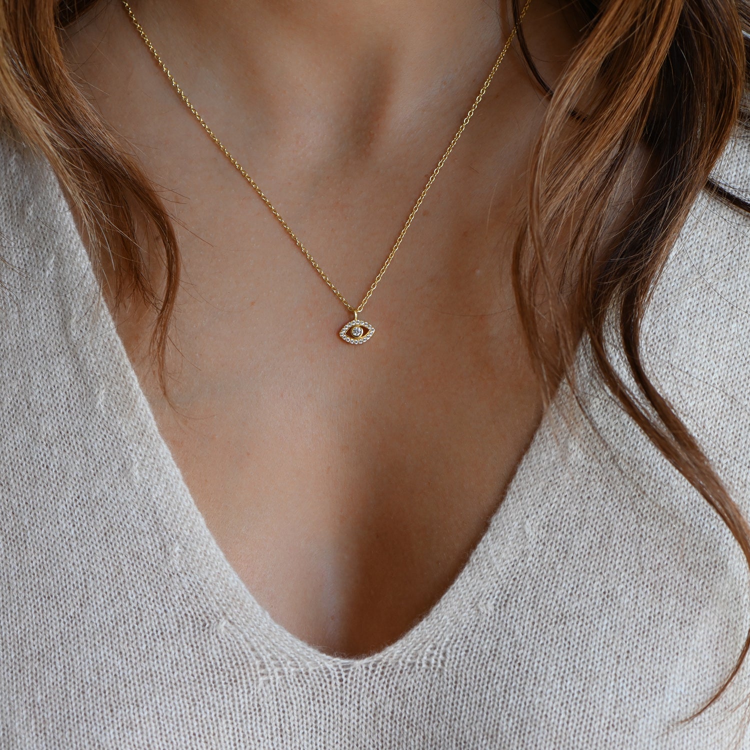 Model wearing delicate gold evil eye studded pendant necklace.