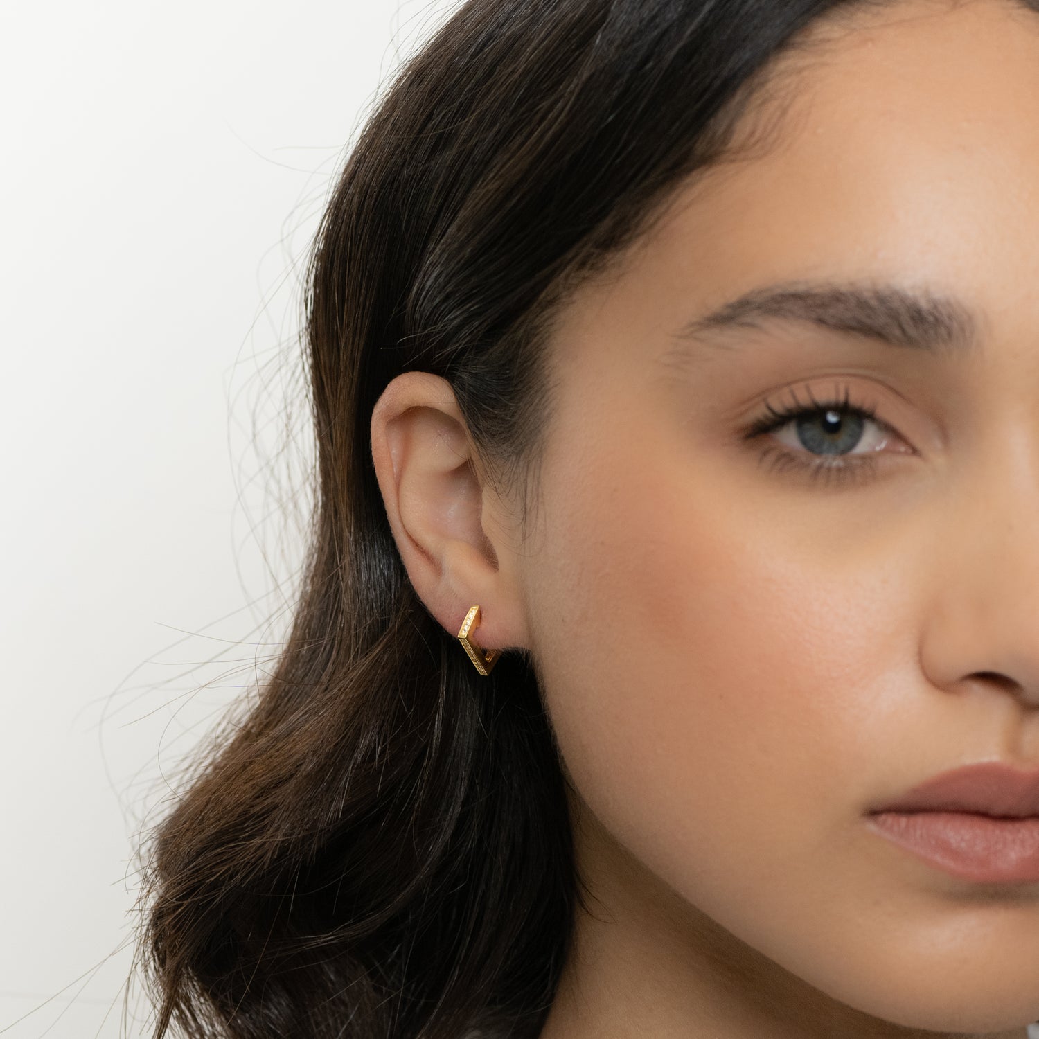 Model wearing minimalist gold geometric earring.