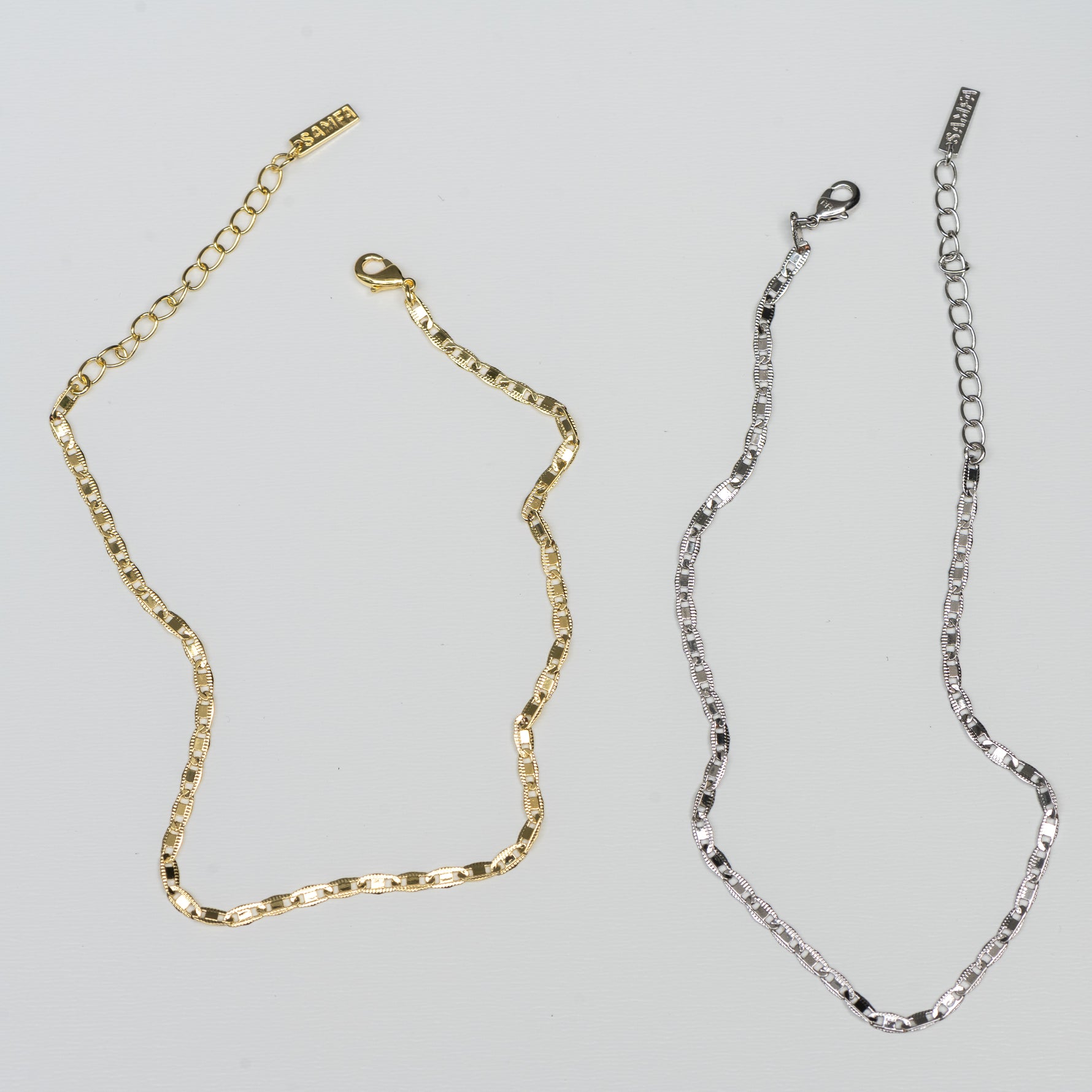 Delicate gold and silver dainty chain ankle bracelets side by side on a plain background