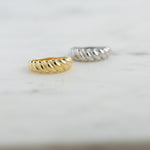 Croissant dome rings in gold and silver in soft studio lighting. 