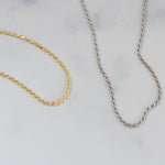 Gold and silver dainty thin rope chain necklaces on a marble background.
