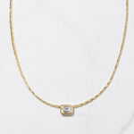 Gold statement baguette bezel pendant necklace on marble background