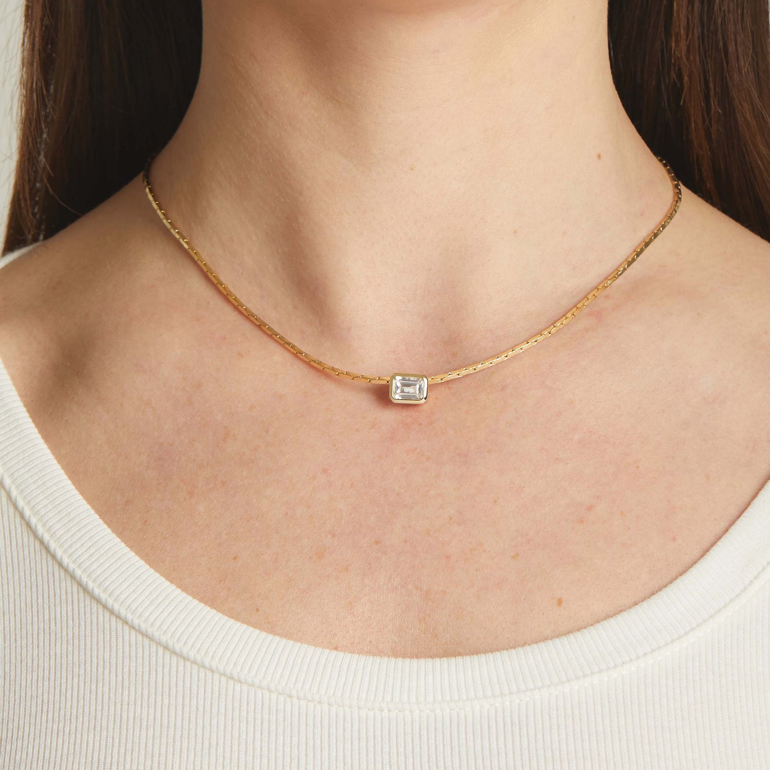 Model wearing statement gold baguette bezel diamond pendant necklace.