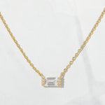 Close-up of baguette stone on a gold chain necklace. 