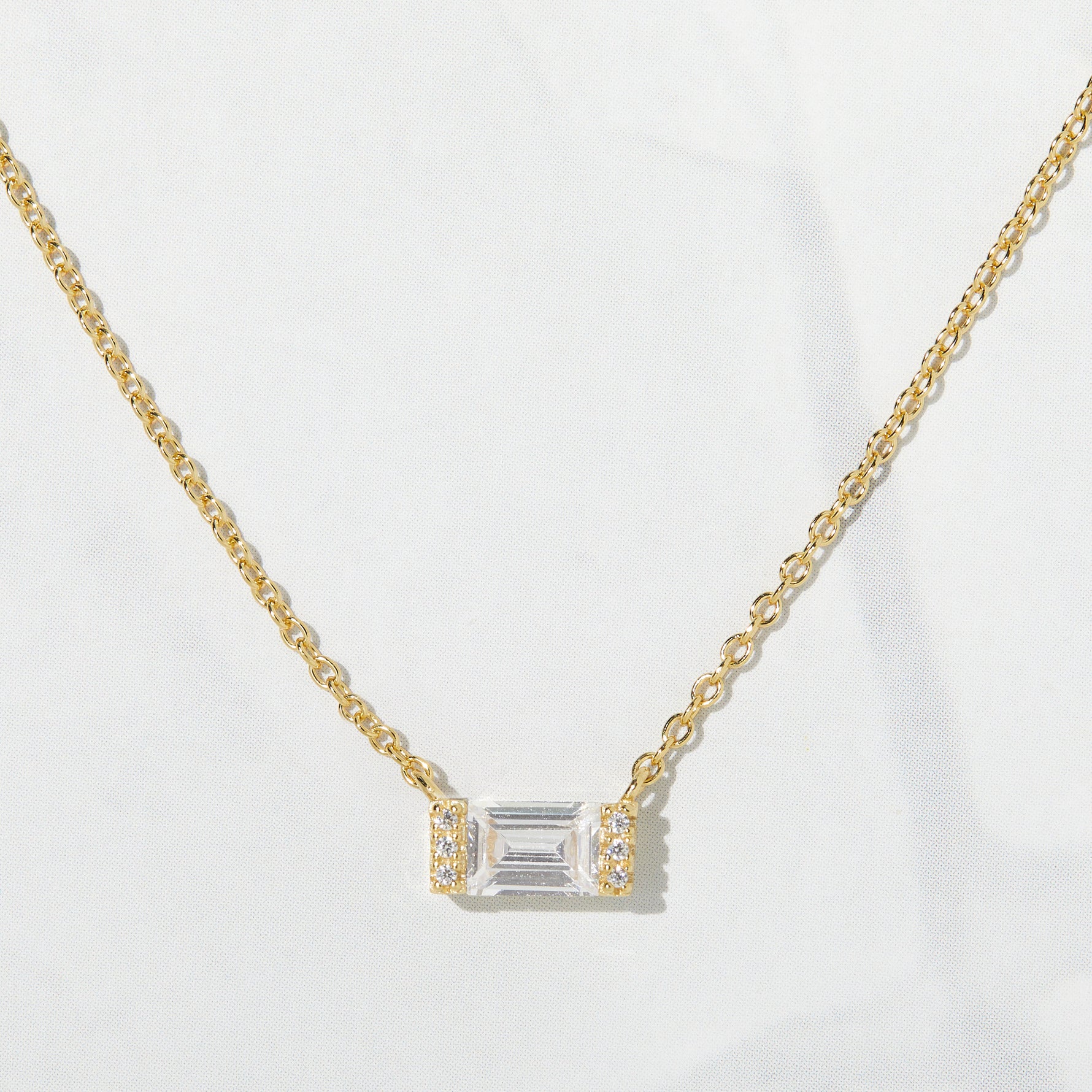 Close-up of baguette stone on a gold chain necklace. 