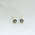Upclose shot of gold flower stud earrings with sapphire birthstone.