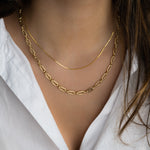 Model wearing two layered chain necklaces featuring a gold thin chain necklace and a statement chain link necklace. 