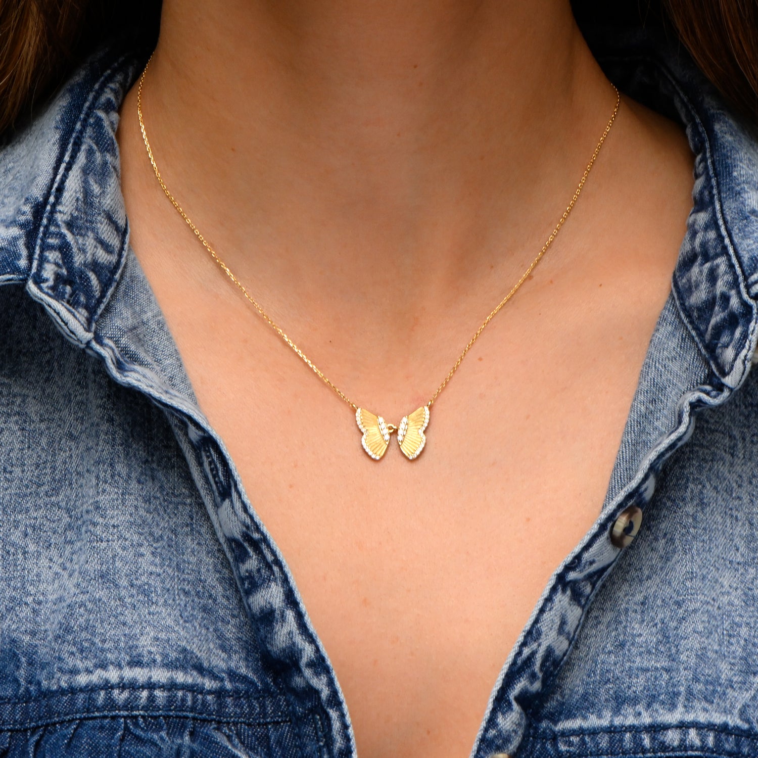 Model wearing gold statement butterfly pendant necklace.