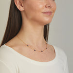 Model wearing sapphire birthstone flower necklace. 