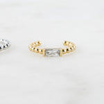 Gold beaded baguette gemstone ear cuff on plain background.