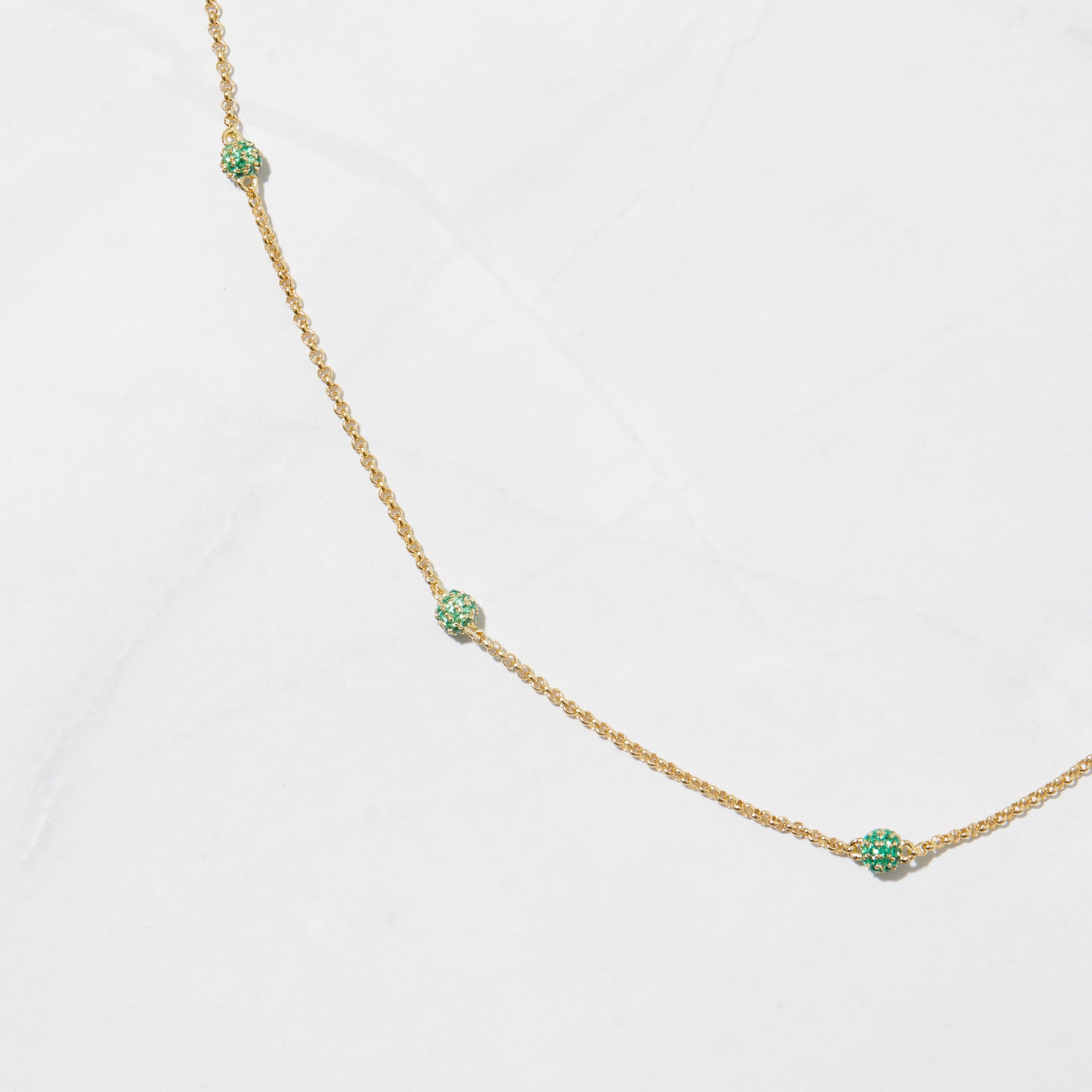 Emerald ball beaded necklace on marble background.