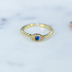 Adjustable beaded ring with sapphire evil eye center. 