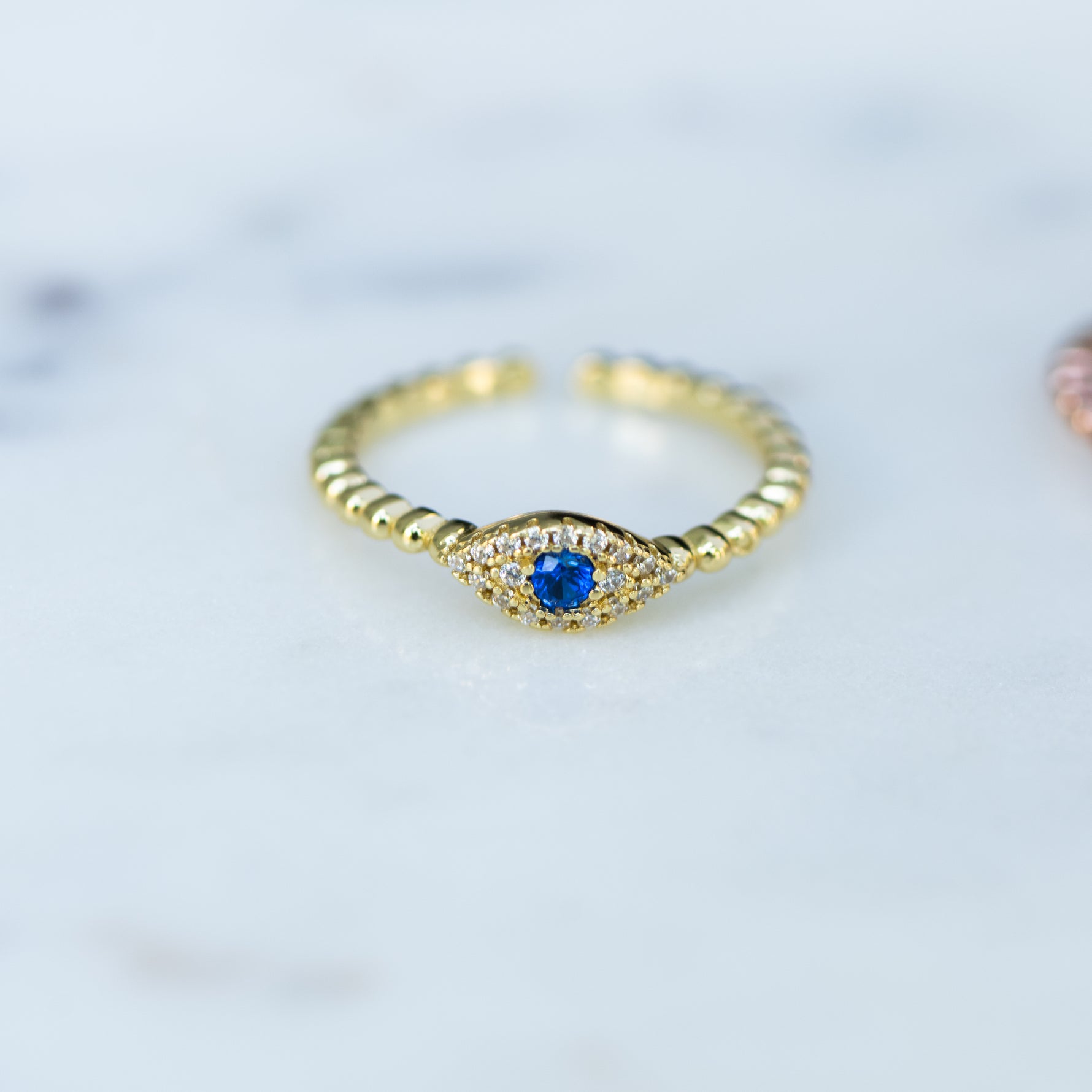 Adjustable beaded ring with sapphire evil eye center. 