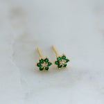 Dainty gold emerald flower stud earrings close up.