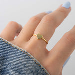 Model wearing delicate gold heart ring.