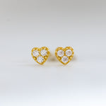 Closeup image of dainty heart cz studded earrings on plain background.