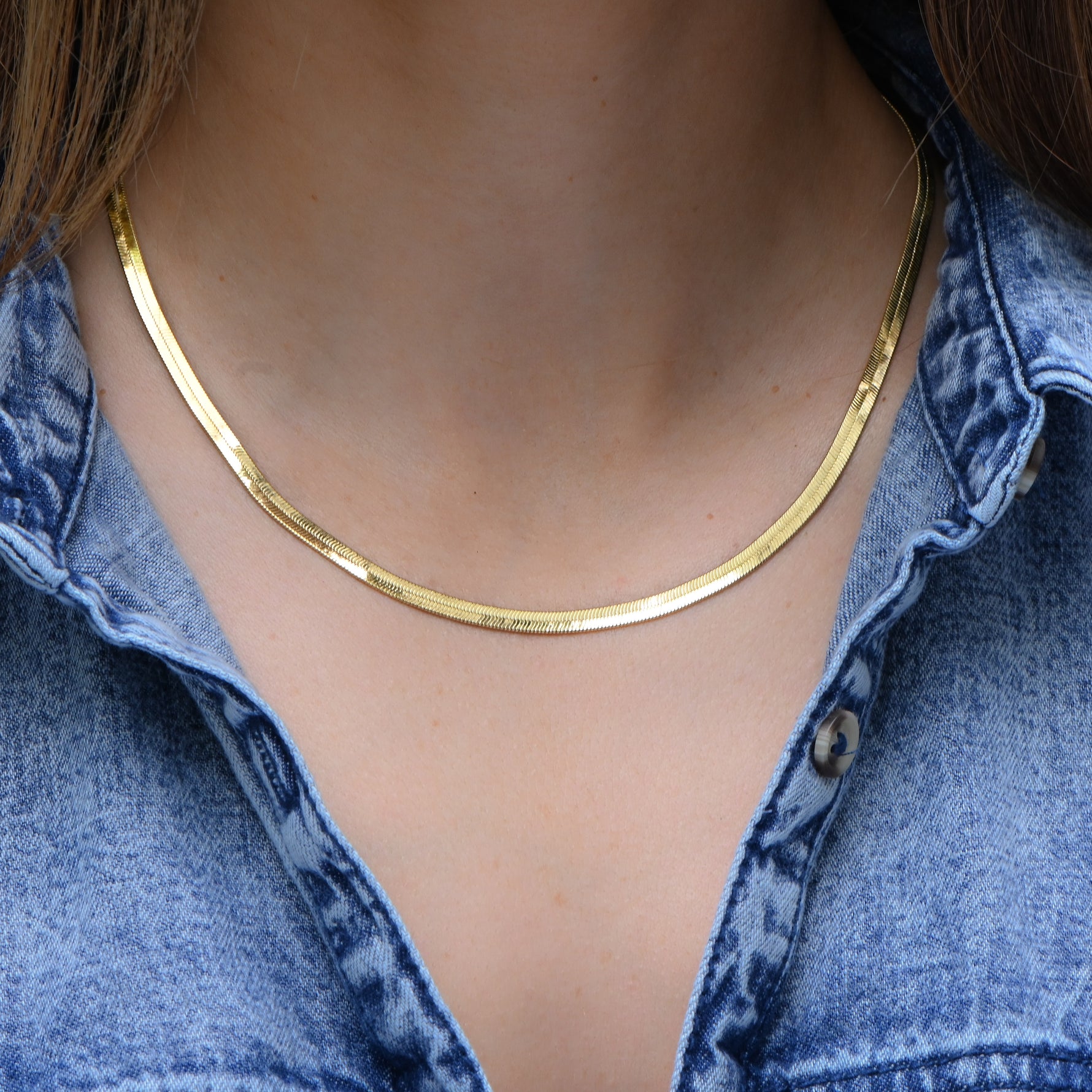Model wearing sleek gold herringbone chain necklace.