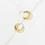 Closeup image of basket gold hoop earrings from the side showing the clasp opening on a marble background.
