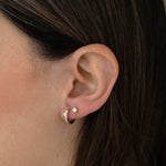 Model wearing minimalist gold hoop earrings with solitaire diamond and bezel studs