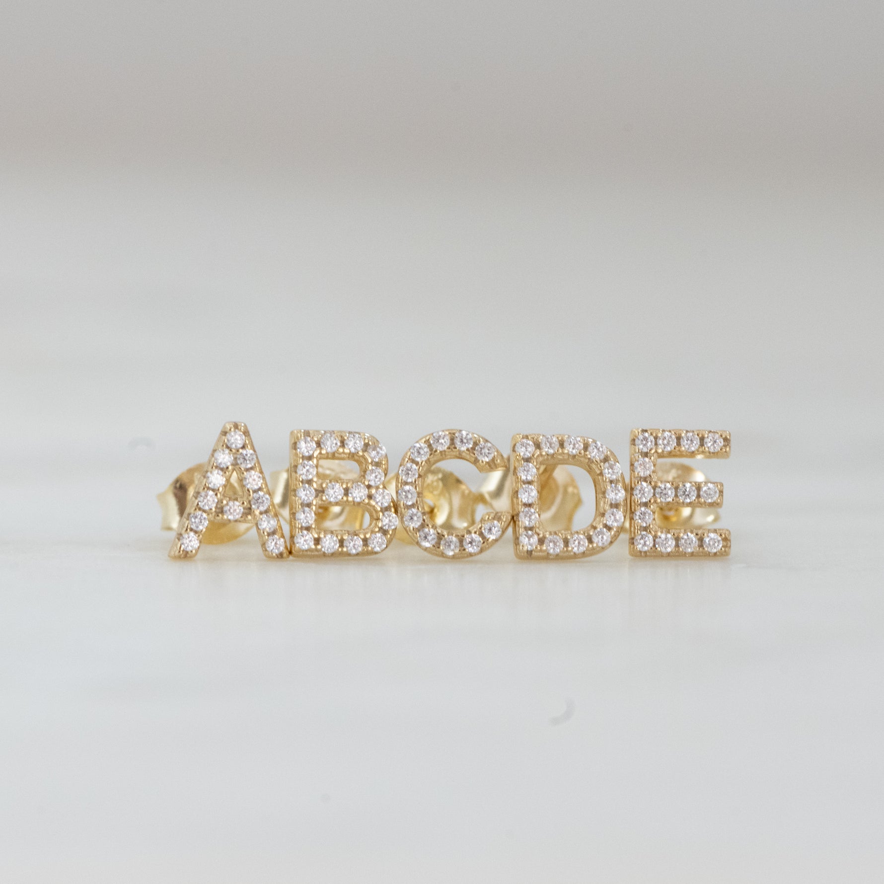 Letters A through E gold stud CZ earrings. 