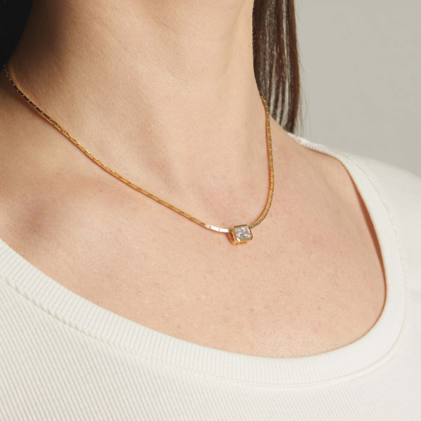 Model wearing minimalist gold baguette bezel pendant necklace on chain.