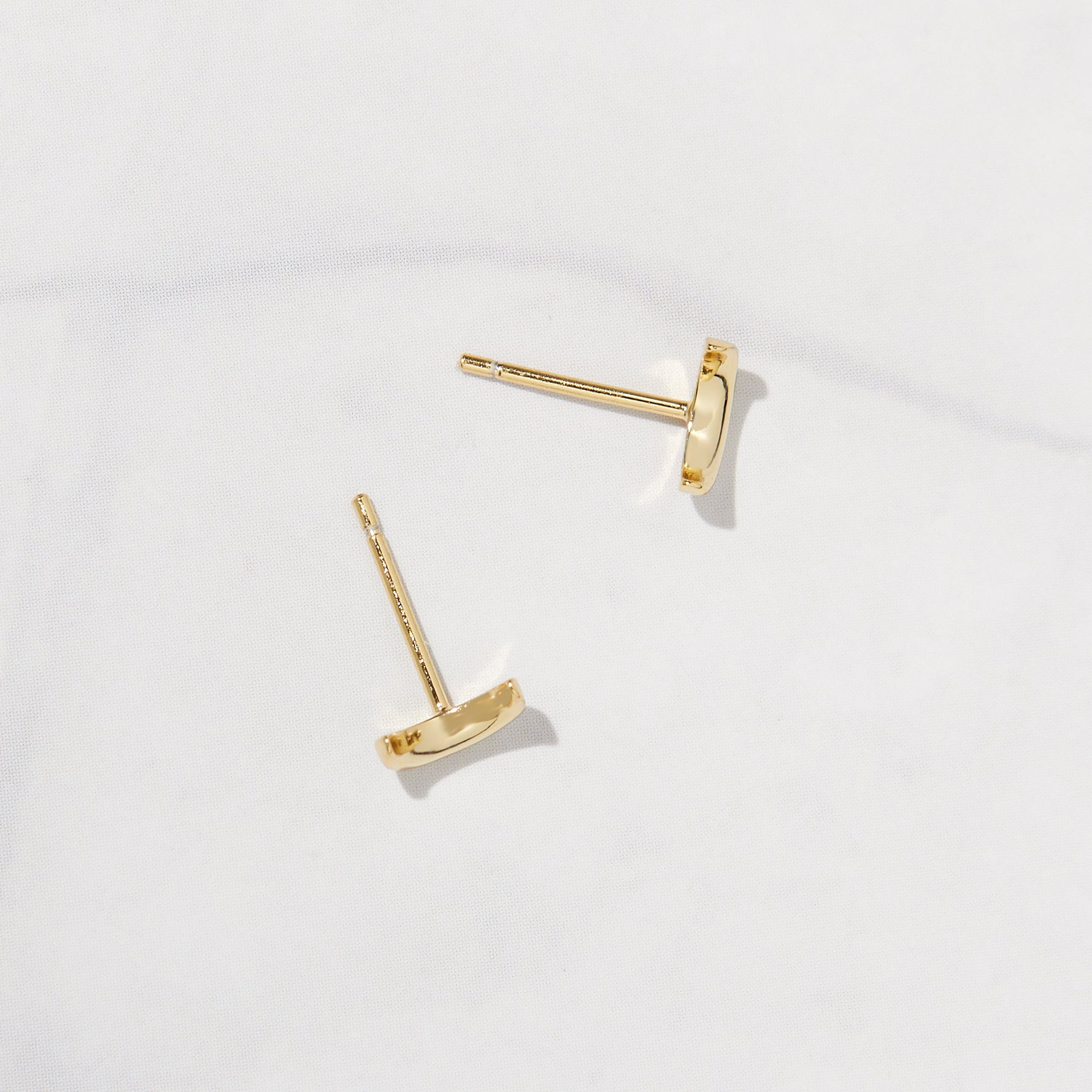 Small gold moon stud earrings with a gold post.