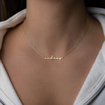 Model wearing gold custom script name necklace with a dainty chain 