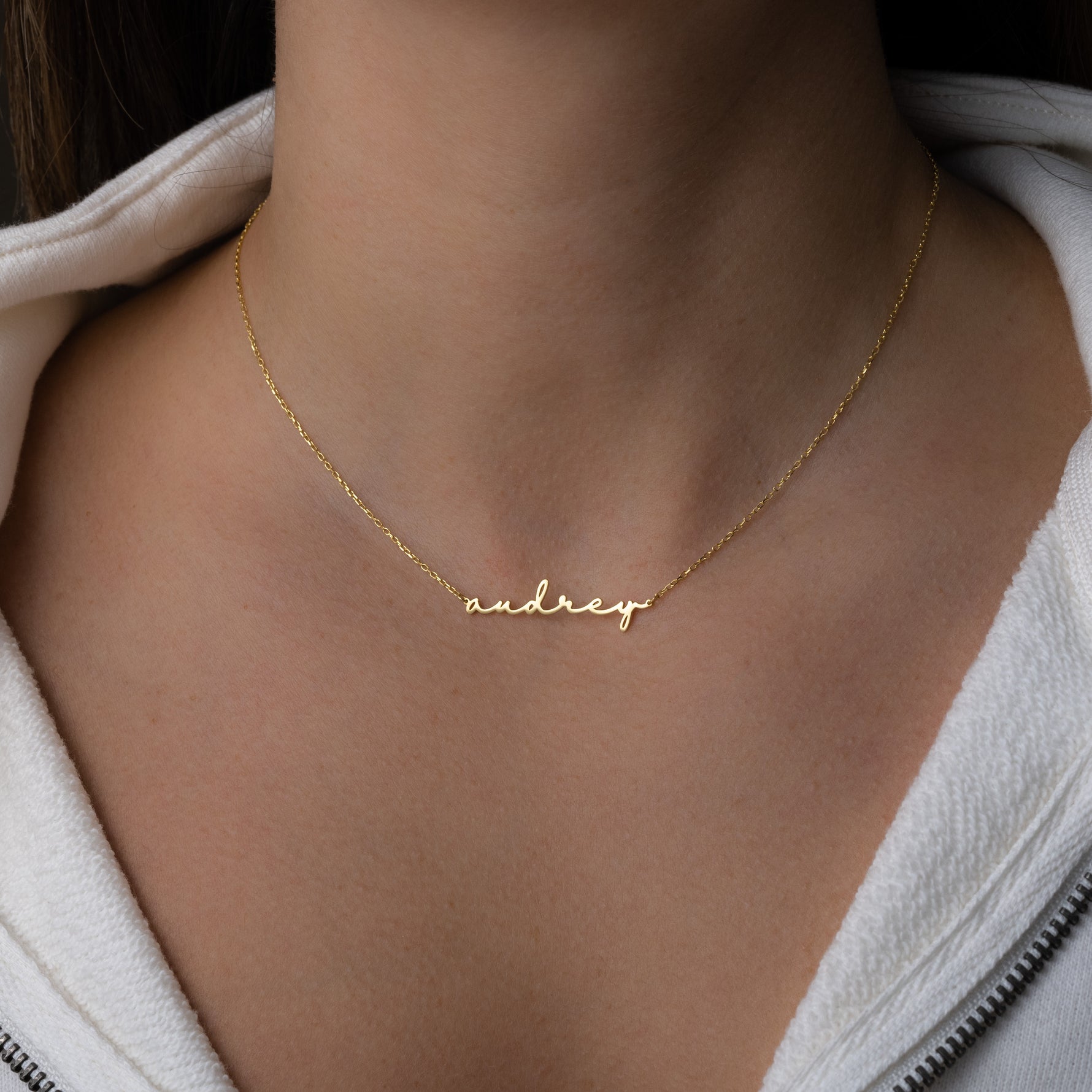 Model wearing gold custom script name necklace with a dainty chain 
