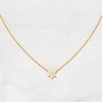 Gold opal flower pendant necklace on plain background