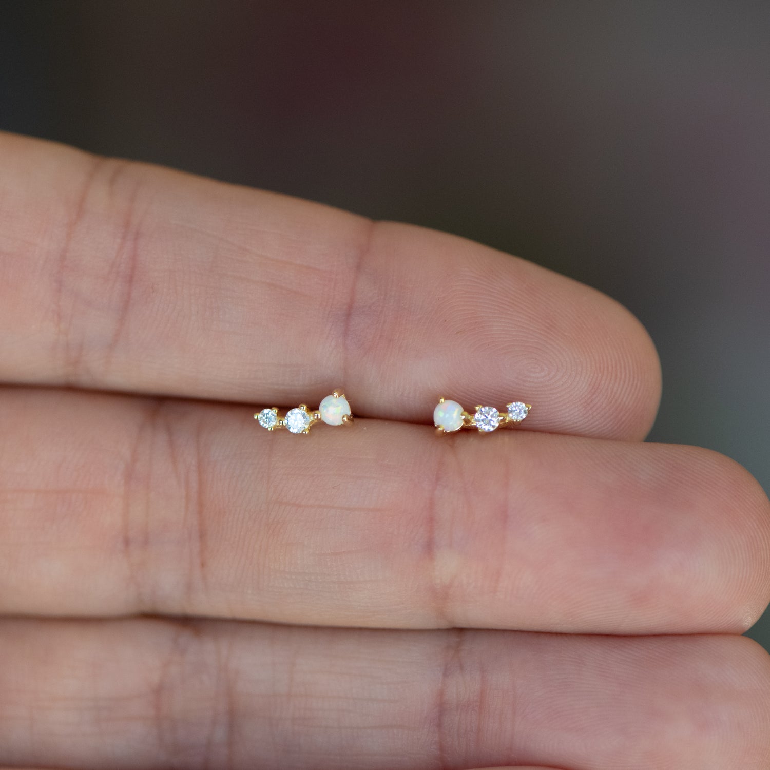 Model holding gold opal and diamond stud earrings