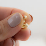 Model holding delicate gold sun opal center stud earrings. 