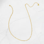 Minimalist gold paperclip chain necklace on a marble surface