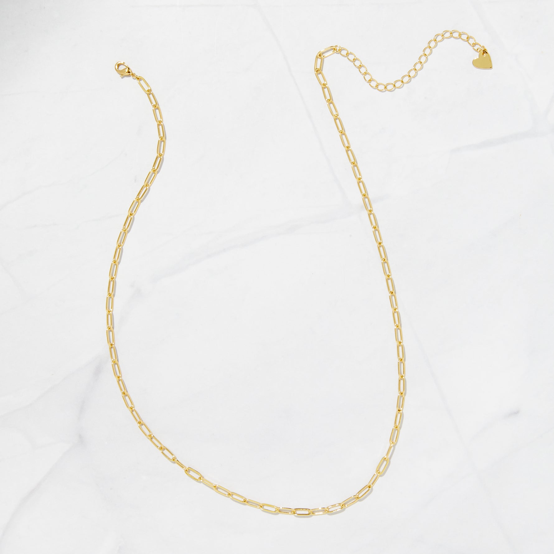 Minimalist gold paperclip chain necklace on a marble surface