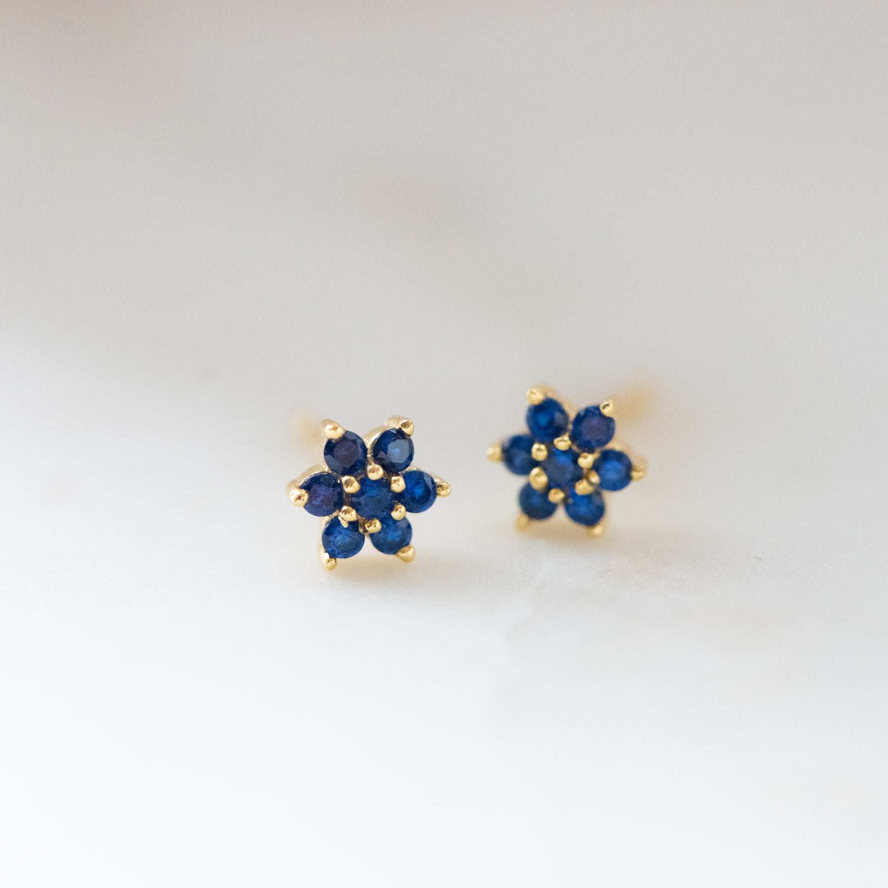 Upclose shot of gold sapphire flower stud earrings.