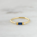 Dainty gold birthstone sapphire ring on marble background. 