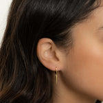 Model wearing dainty gold spike charm earrings