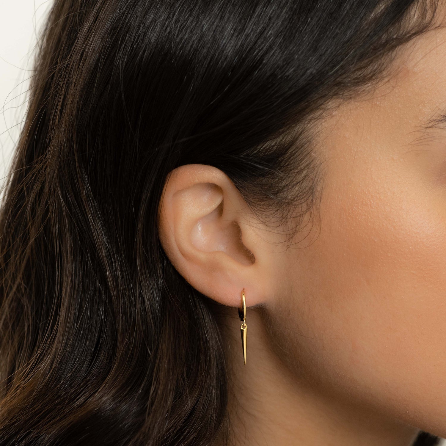 Model wearing dainty gold spike charm earrings