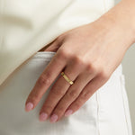 Model wearing sleek gold ridged band ring. 