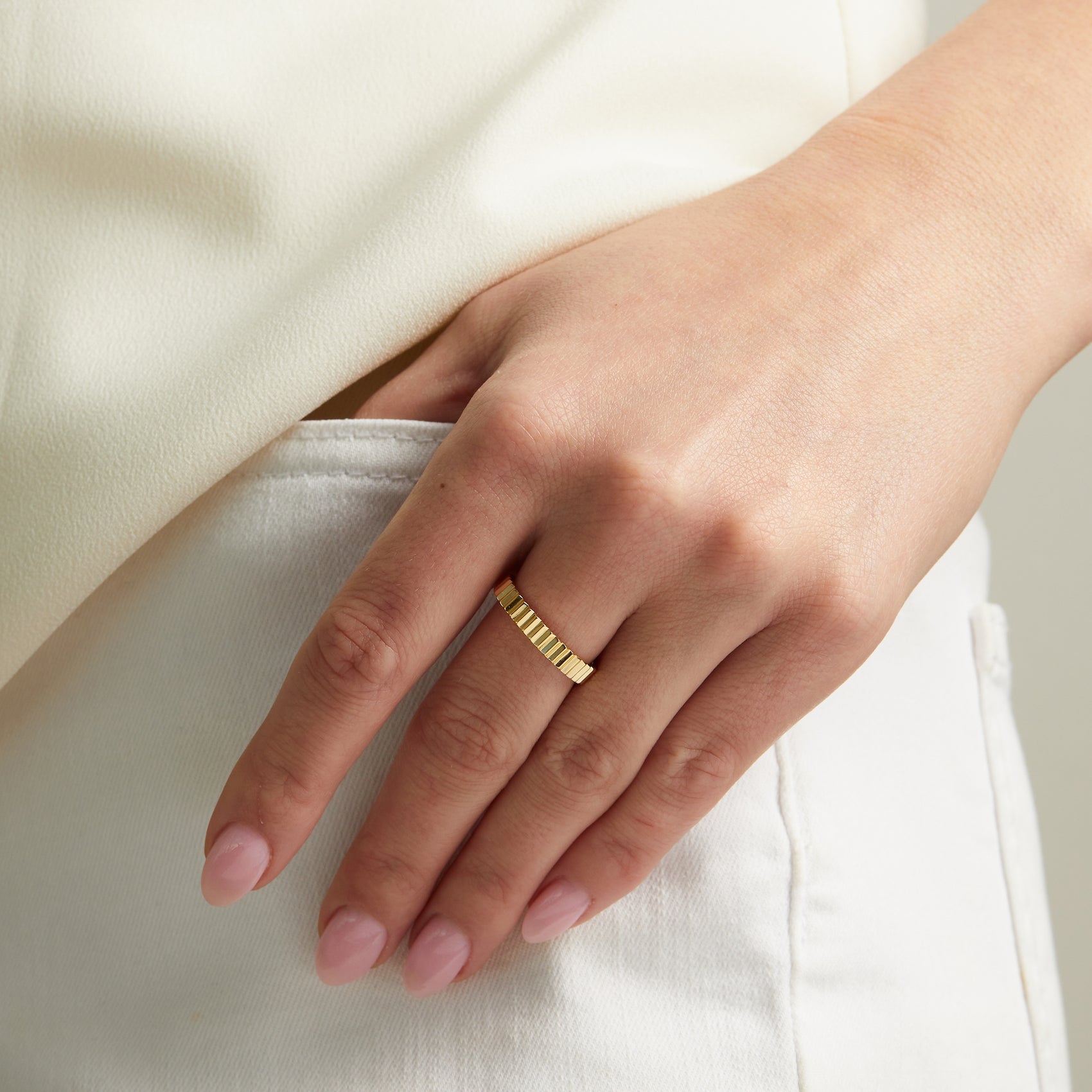 Model wearing sleek gold ridged band ring. 