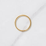 Textured gold ring from the side on a marble background. 