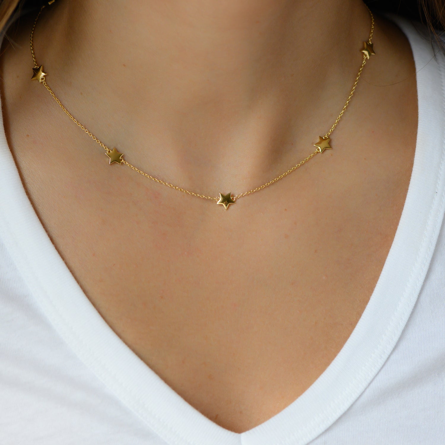 Model wearing minimalist gold star charm necklace.