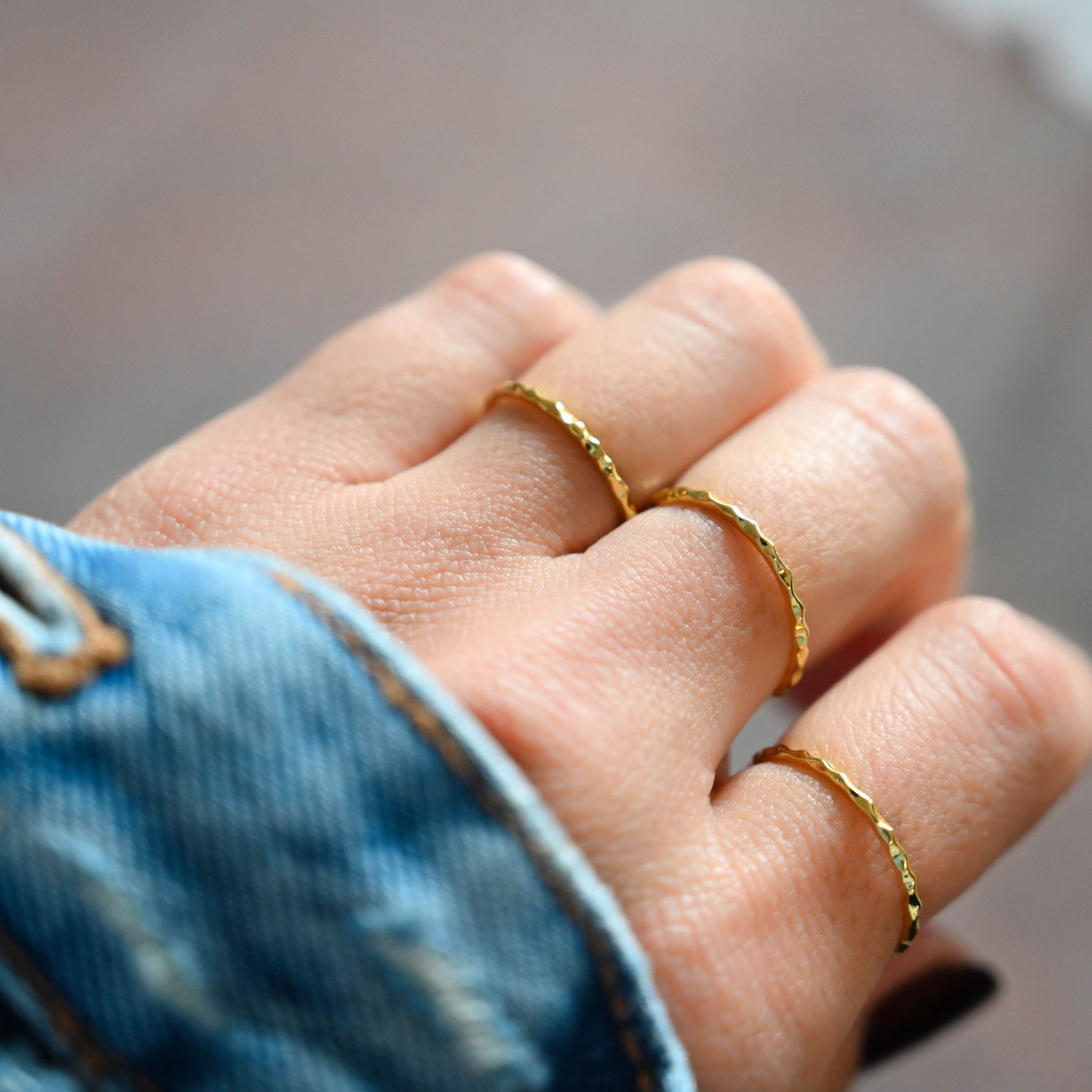 Model wearing gold minimalist ring stack featuring dainty textured rings. 