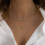 Model wearing delicate gold turquoise beaded necklace layered with a turquoise evil eye necklace. 