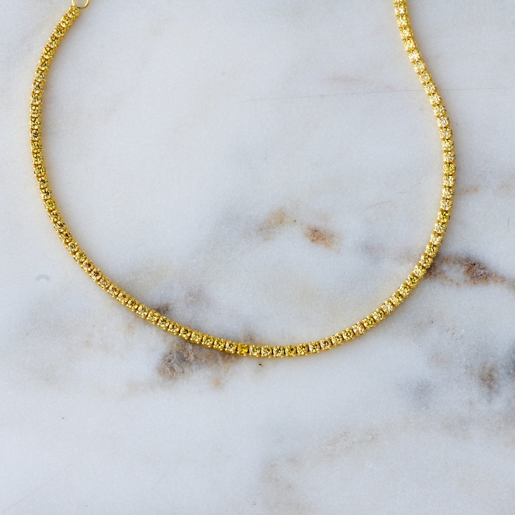Up close shot of yellow tennis ankle bracelet